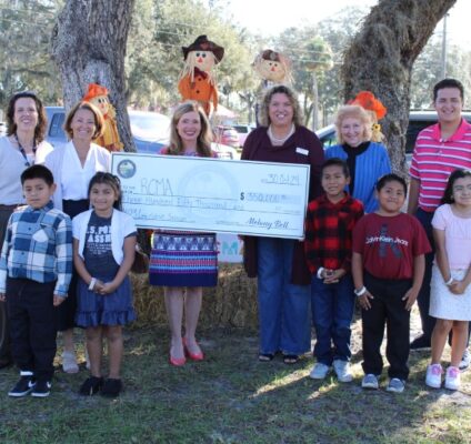 Representative Melony Bell presents a $350,000 check to RCMA Mulberry Community Academy staff and students, celebrating funding for a water treatment system.