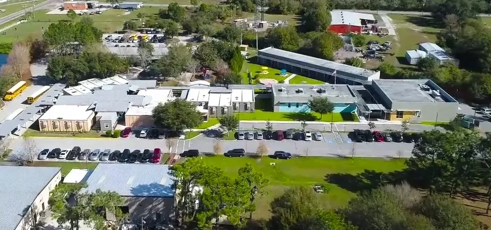 Aerial view of the RCMA Wimauma Community Academy campus showing school buildings, parking lots, and green fields.