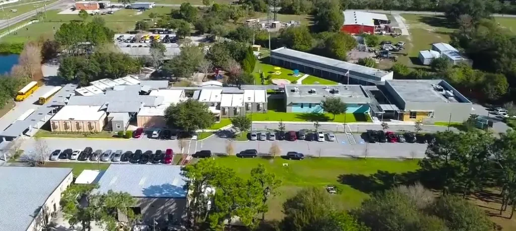Aerial view of the RCMA Wimauma Community Academy campus showing school buildings, parking lots, and green fields.
