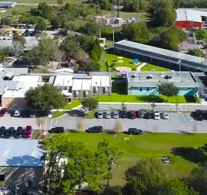 Aerial view of the RCMA Wimauma Community Academy campus showing school buildings, parking lots, and green fields.